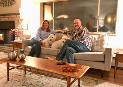 Photo of Holly and Joe at home on the couch with their dogs, Ciro and Fergus